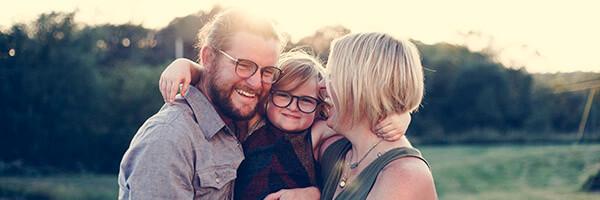 Seguro de Vida - Familia felices mientras que sonríen y se abrazan en el campo Seguro de Vida - Familia felices mientras que sonríen y se abrazan en el campo