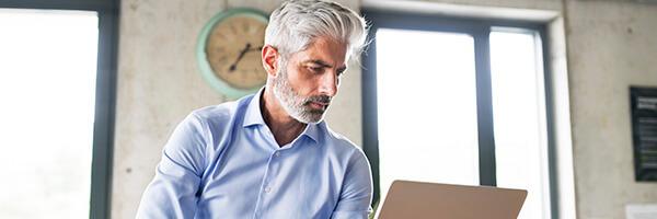 Servicio de Valores Online - Hombre de negocios sentado con su portatil en la oficina Servicio de Valores Online - Hombre de negocios sentado con su portatil en la oficina