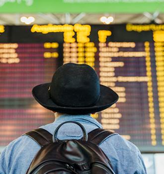 Guías Ruralvía Operativa Internacional - Persona mirando panel de salidas y entradas de trenes o aviones