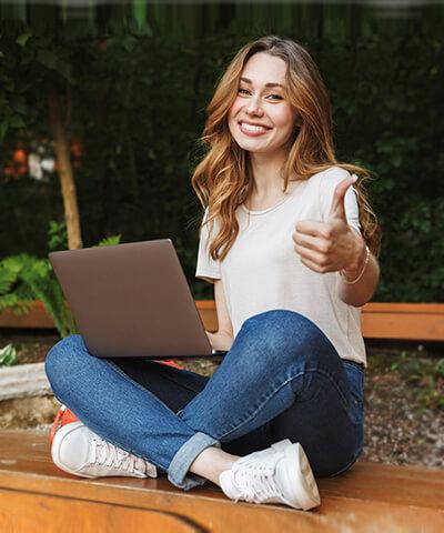 Ventajas para particulares - Joven chica sonriendo sentada utilizando un portatil